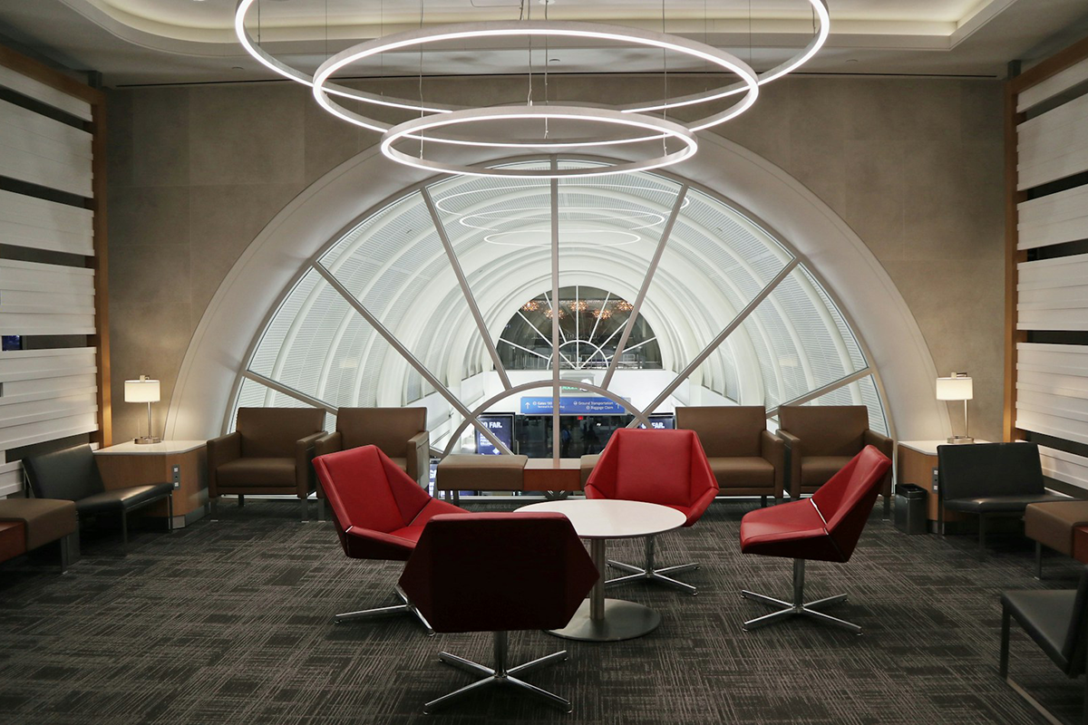 Empty airline lounge with red chairs and a view over the terminal
